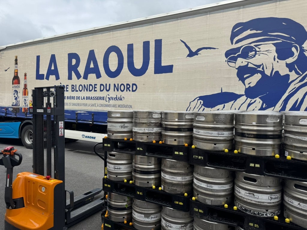 Camion de livraison MON ALCOOL et fûts de bière sur palettes devant un entrepôt